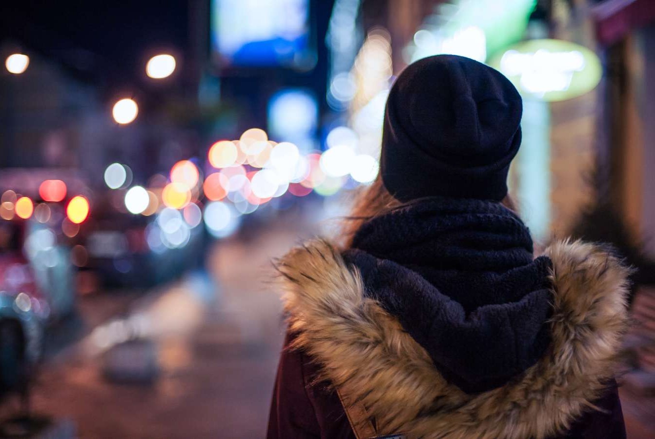 back of woman's head walking down high street at night alone